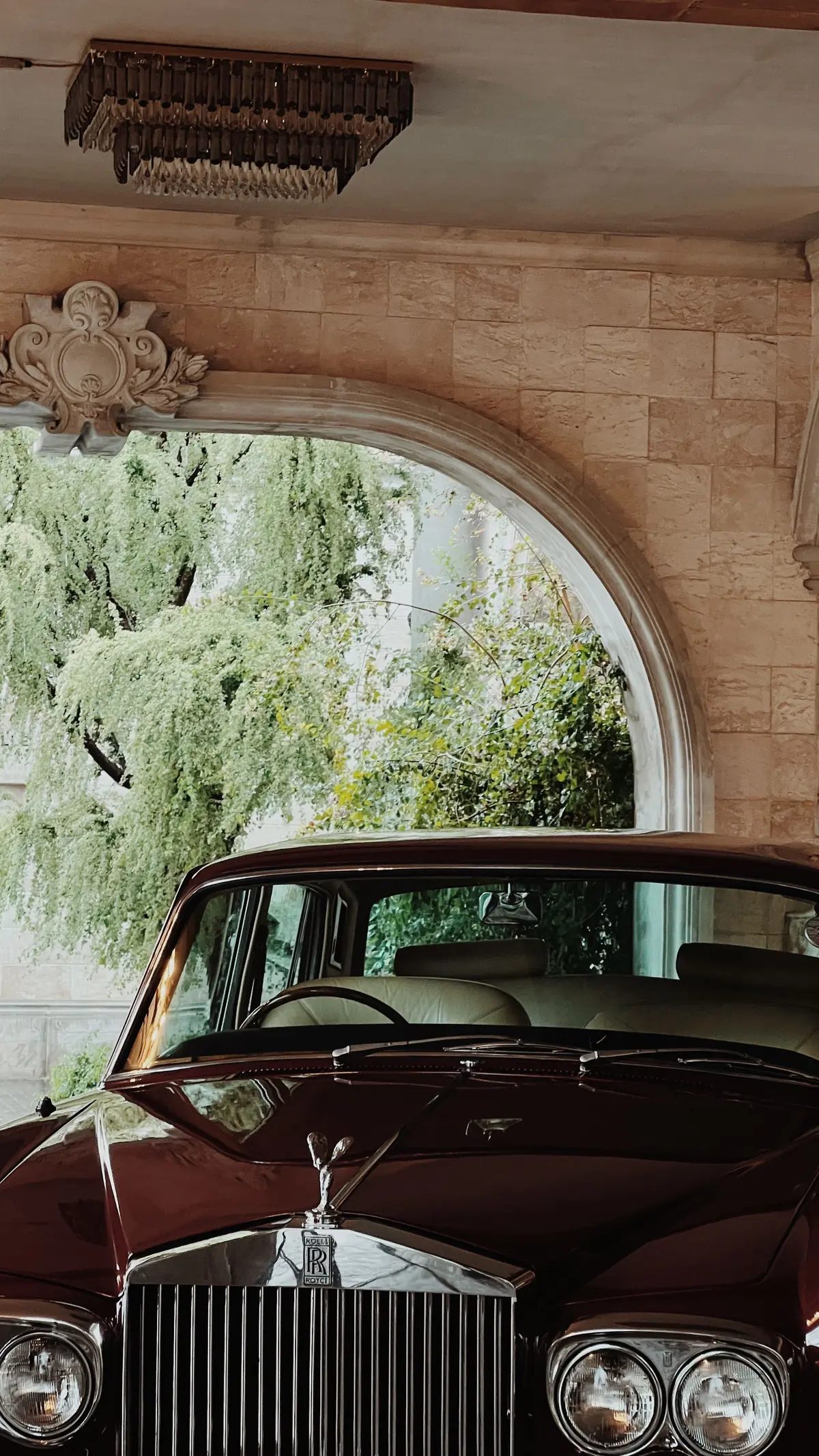 A vintage car parked under a stone archway at golden hour.